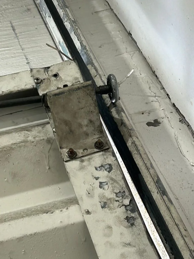 Close-up of weathered commercial overhead door top roller fixture and track guide bracket