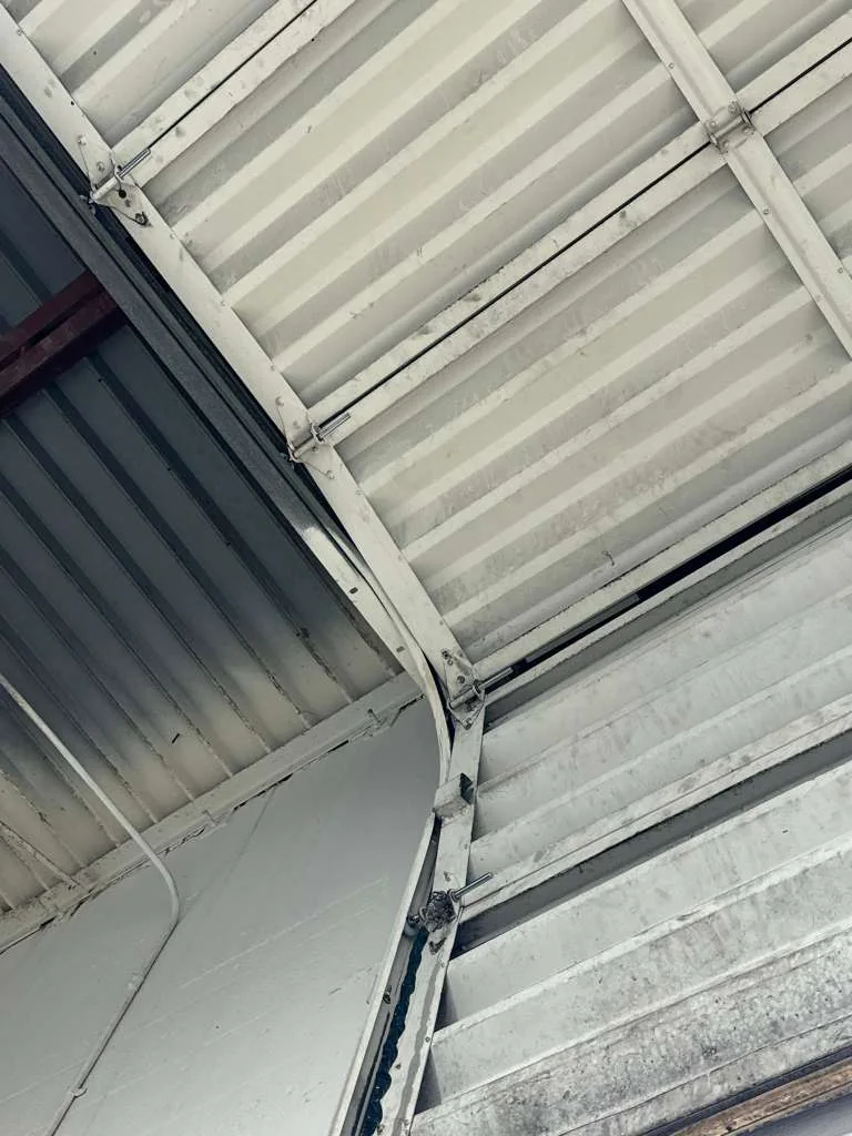 Commercial warehouse overhead door curved radius track, vertical rail, and corrugated metal door panels