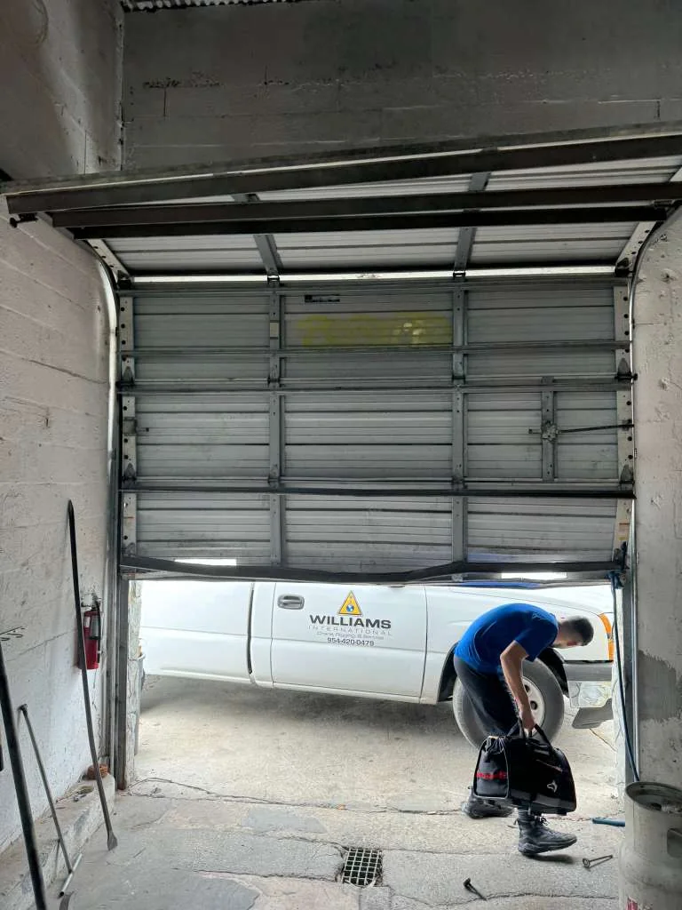 Quick Springs technician arriving with tool bag to service crooked commercial overhead warehouse door