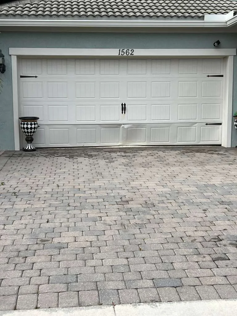 White carriage-style garage door with dented bottom panel