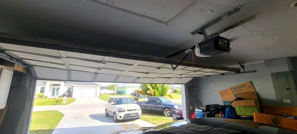 Double garage door smoothly opened overhead along horizontal tracks revealing sunny Florida driveway