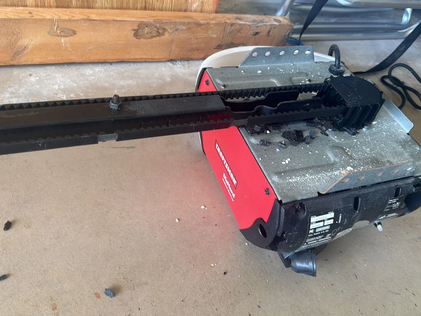 Broken Craftsman opener motor on floor showing stripped rubber drive belt and debris