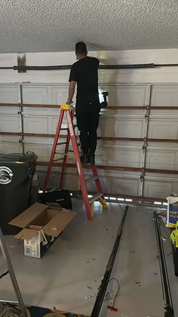 Quick Springs technician on ladder assembling and hanging new Chamberlain belt-drive garage door opener