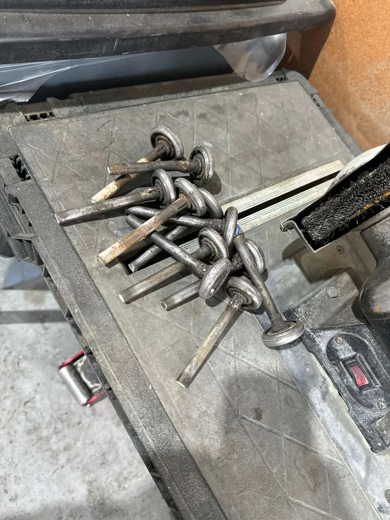 Pile of rusty, worn steel garage door rollers replaced during tune-up and hardware overhaul